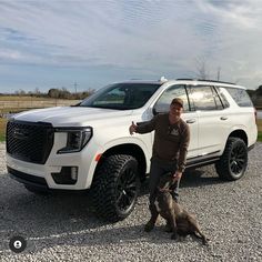 a man standing next to a white truck with two dogs sitting in front of it