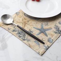 a place mat with a spoon and starfish design on it next to a plate