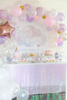 a dessert table with balloons, cake and cupcakes