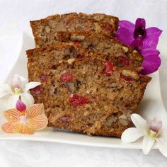 two slices of fruitcake on a plate with orchids and flowers in the background