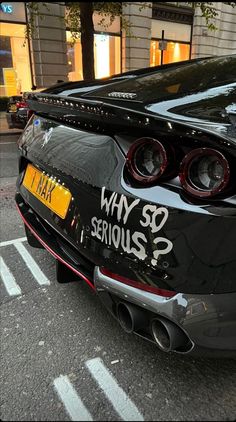 the back end of a black sports car with graffiti on it