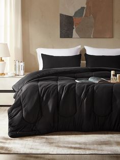 a bed with black comforter and pillows in a room next to a painting on the wall