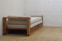 a couch sitting on top of a wooden floor next to a white brick wall