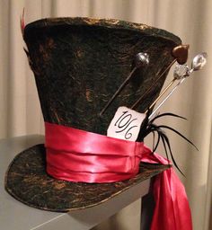 a hat with a red ribbon around the brim is sitting on top of a table