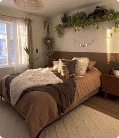 a large bed sitting in a bedroom next to a window with plants on the wall