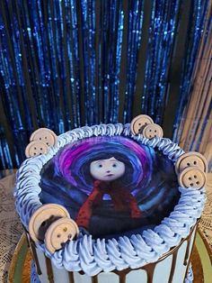 there is a cake decorated with buttons and a girl on the top it sits on a table