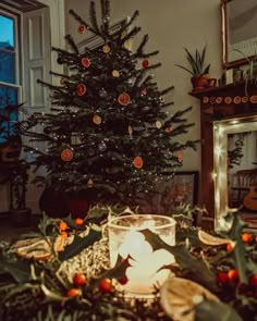 a decorated christmas tree in the corner of a living room with a lit candle next to it