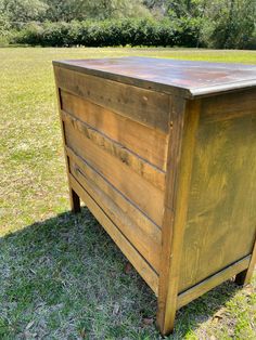 a wooden chest sitting on top of a grass covered field