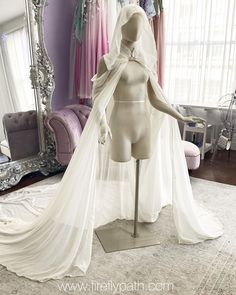 a mannequin wearing a wedding dress in front of a mirror with pink curtains