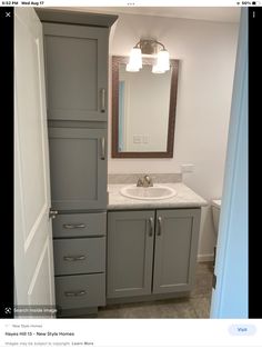 a bathroom with gray cabinets and a white sink