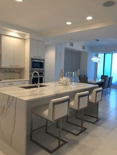 a kitchen with marble counter tops and white chairs