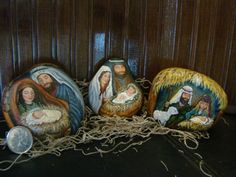 three nativity rocks with the birth of jesus and mary on them, all painted in different colors