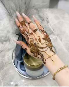 a woman's hand with hennap on top of it and some feathers in the background