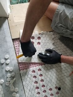 a man in black gloves working on a tile floor