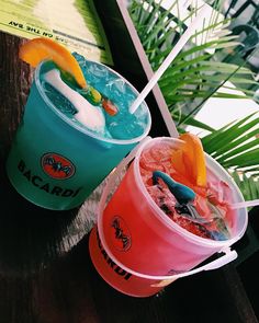 two buckets filled with drinks sitting on top of a table next to each other