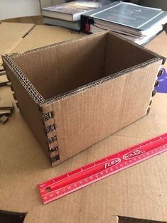 a cardboard box sitting on top of a table next to a ruler and some books