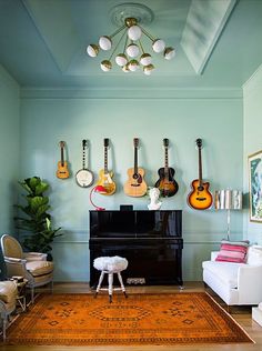 a living room with guitars on the wall and a piano in the middle of the room