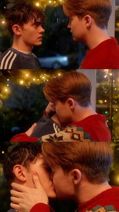 two young men kissing each other in front of a christmas tree