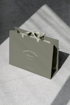 a gray shopping bag sitting on top of a cement floor next to a white wall