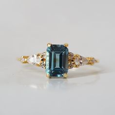 an emerald and diamond ring on a white surface