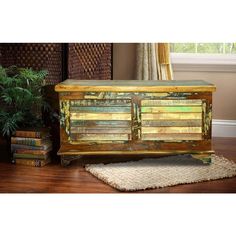 an old chest with books on it in a room next to a potted plant