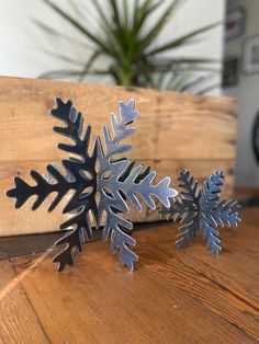 two metal snowflakes sitting on top of a wooden table