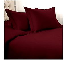 a bed with red sheets and pillows on it