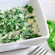 a white bowl filled with cheese and spinach