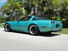 a blue sports car parked in front of some palm trees