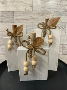 three wooden blocks decorated with wood beads and leaves