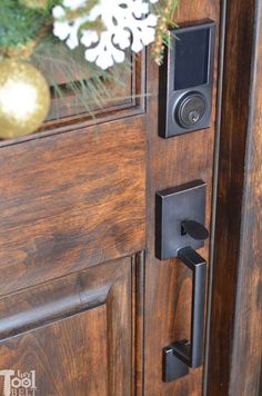 a close up of a door handle on a wooden door with flowers in the background