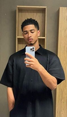 a man taking a selfie with his cell phone in front of a bookcase