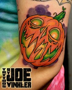 a person with a tattoo on their arm has an orange jack - o - lantern