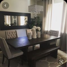 a dining room table with two chairs and a bench in front of the mirror on the wall