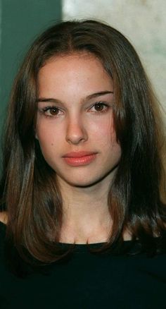 a close up of a person wearing a black shirt and long hair with brown eyes