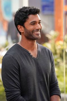 a man smiling while standing next to a pole