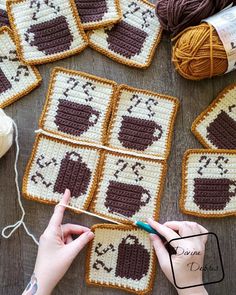 someone crocheting coffee mugs in squares on a table