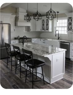 a kitchen with white cabinets and marble counter tops, black chairs and an island in the middle