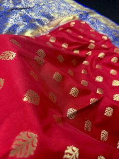 Stunning Saree!! Red body with Blue and on the borders and pallu. Floral Jaal design on the borders with golden Zari Work. The buttas on the body are golden Zari Work. Super Soft Saree. Color : Red with Blue Base Fabric : Banarasi Silk Blouse piece : Comes with Blouse pieceBlouse material : Banarasi Silk Fall & Edging: Comes with Fall and edging (Pico) and tassels attached Disclaimer :-- Color variation is possible due to various reasons like phone or desktop setting, resolution etc. Please don' Red Paithani Silk Traditional Wear With Motifs, Red Chanderi Traditional Wear With Motifs, Red Paithani Silk Saree For Navratri, Red Chanderi Traditional Wear For Celebration, Red Paithani Silk Unstitched Saree, Red Unstitched Paithani Silk Saree, Red Banarasi Silk Blouse Piece With Pallu, Red Paithani Silk Traditional Wear With Traditional Drape, Red Paithani Silk Blouse For Puja