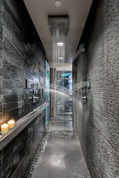 a long narrow hallway with candles on the wall and black tiled walls in the background