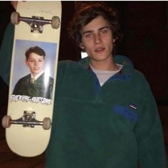 a young man holding up a skateboard with an image of him on the board