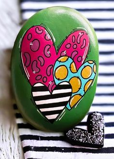 a green button with two hearts painted on it next to a black and white striped object