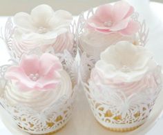 three cupcakes decorated with pink and white frosting on a cake platter