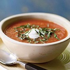 a white bowl filled with soup on top of a plate next to a silver spoon