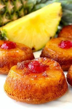 pineapple upside down cakes on a white plate next to sliced pineapples and a pineapple