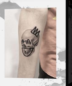 a skull with a crown tattoo on the arm