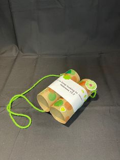 an orange and green paper bag with a string attached to it on a gray surface