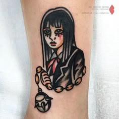 a woman with long black hair wearing a red tie and holding a clock tattoo on her leg