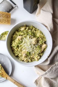 a white bowl filled with broccoli rice next to a grater and wooden spoon