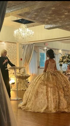 a woman standing in front of a mirror wearing a gold dress and looking at her reflection